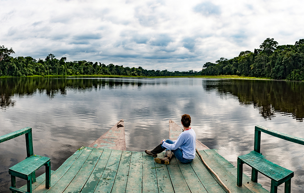 Eine Touristin betrachtet den Dschungel auf einem Boot der Ñape Lodge im Amazonas bei Tambopata