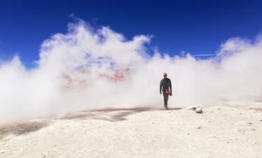 Ein Tourist kommt aus einer Dampfwolke eines Geysirs in der Salar de Uyuni
