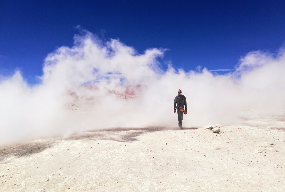 Ein Tourist kommt aus einer Dampfwolke eines Geysirs in der Salar de Uyuni