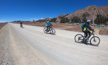 Radfahrer fahren mit eBikes auf einer Halbinsel am Titicacasee
