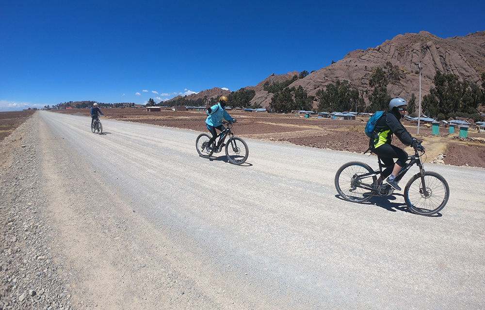Radfahrer fahren mit eBikes auf einer Halbinsel am Titicacasee