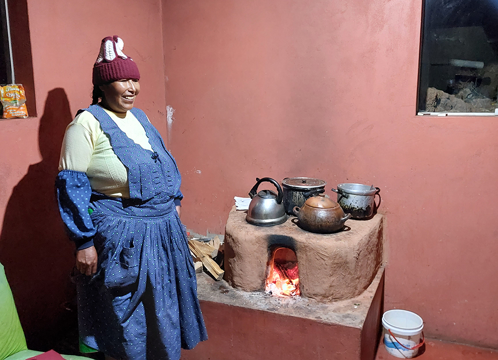 Eine Frau kocht auf einem traditionellen Kochherd in der Luquina Chico Lodge am Titicacasee