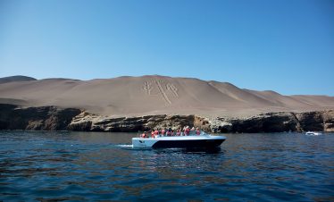 Touristen fahren mit dem Boot am Kandelaber im Naturschutzgebiet Paracas vorbei