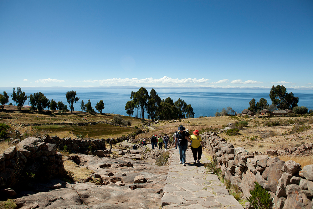 Touristen laufen den Weg hoch auf der Insel Taquile im Titicacasee