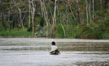 Ein kleiner Junge fährt mit dem Kanu auf einem Fluss im Amazonas in der Umgebung der Treehouse Lodge in Iquitos