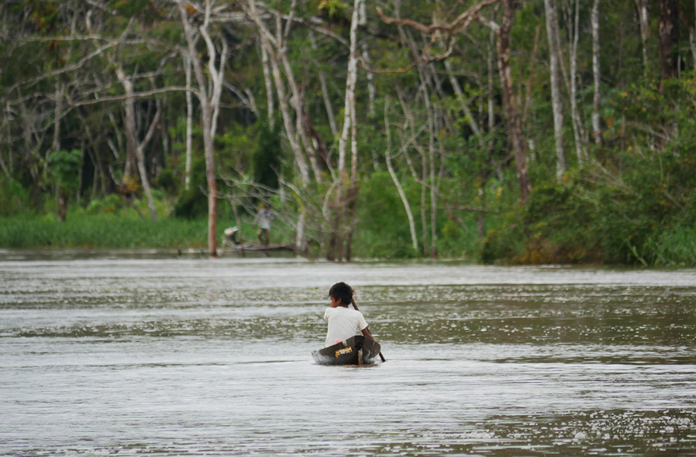 Ein kleiner Junge fährt mit dem Kanu auf einem Fluss im Amazonas in der Umgebung der Treehouse Lodge in Iquitos